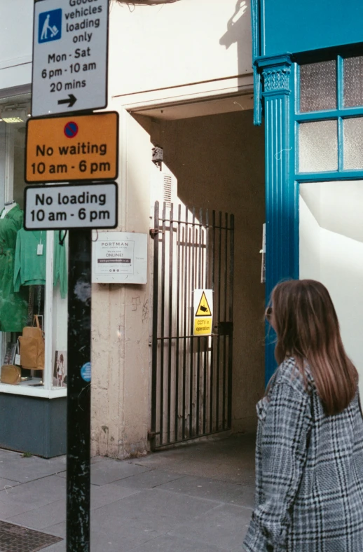 woman walking on street next to building with signage