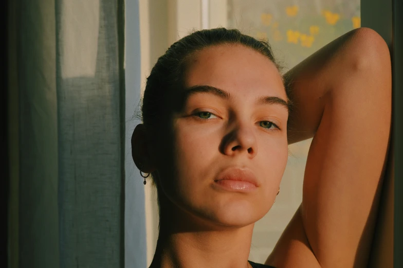 a woman sitting with her head up by a window