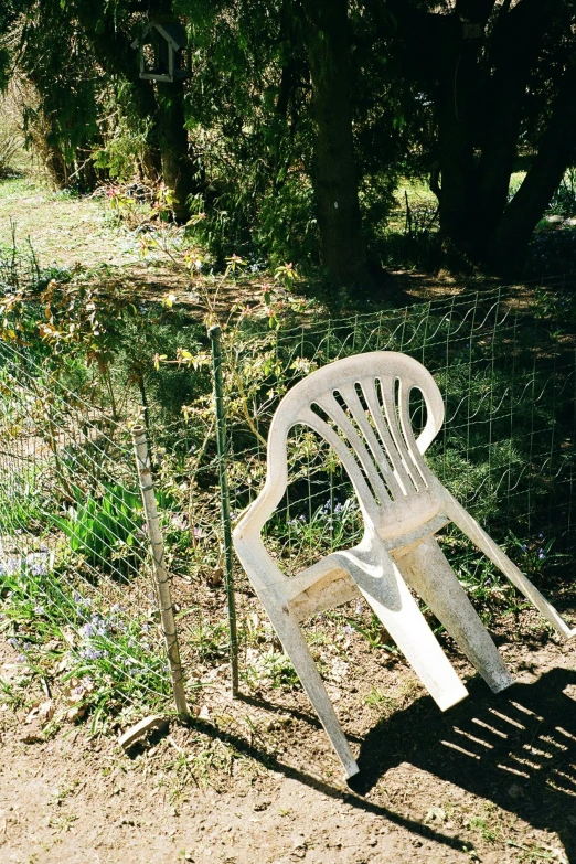 a white plastic chair sitting by a fence