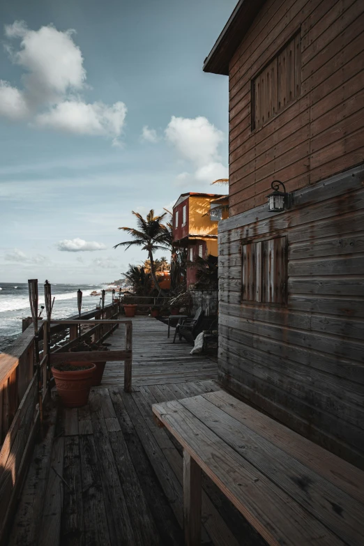 an empty deck on the ocean side of an old house