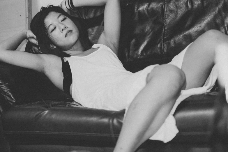 woman in a white dress laying on top of a leather chair