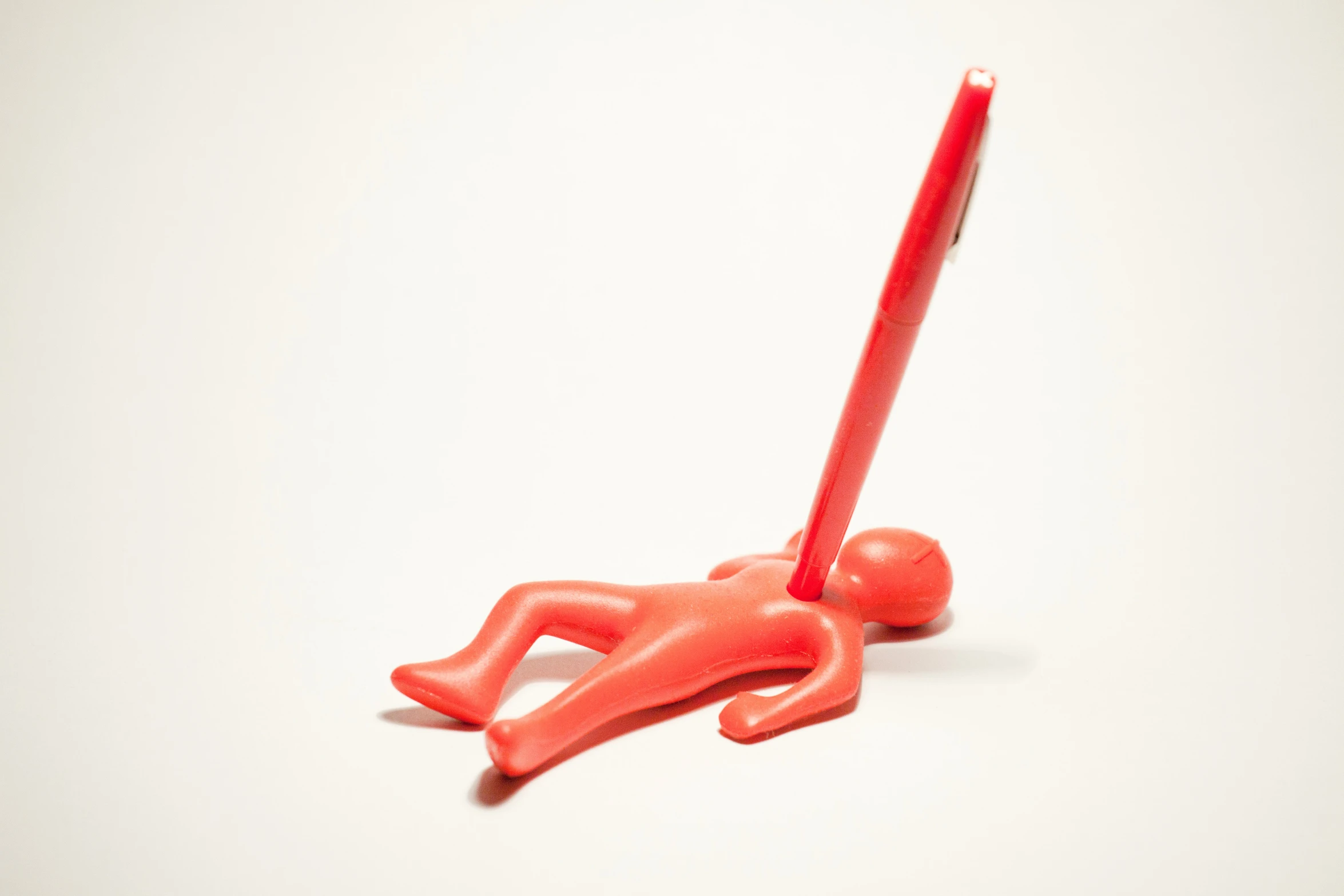 a plastic figure is holding a red plastic pen