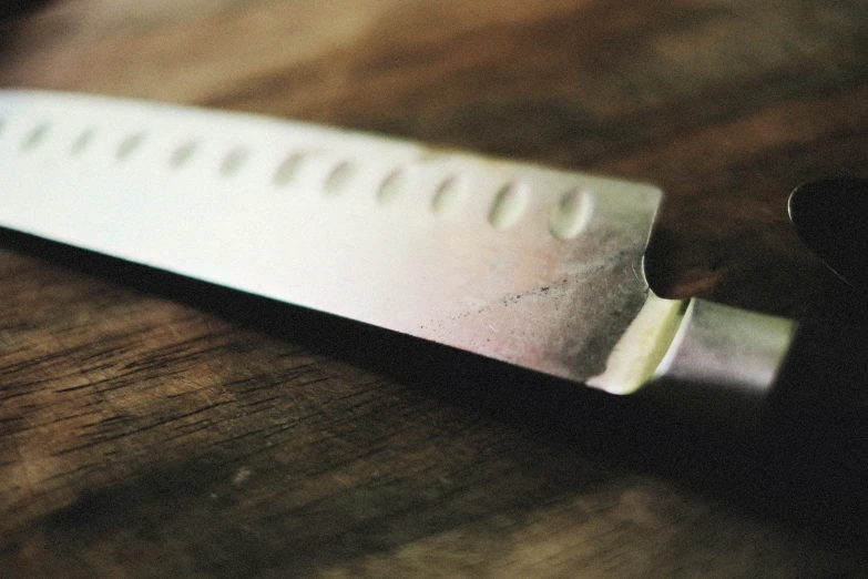 a close up s of a knife laying on the wooden table