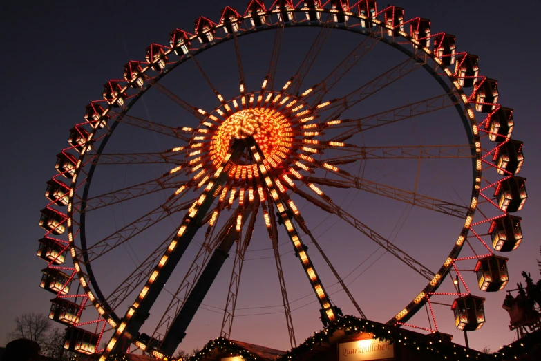 an illuminated ferris wheel at night with many lights on it