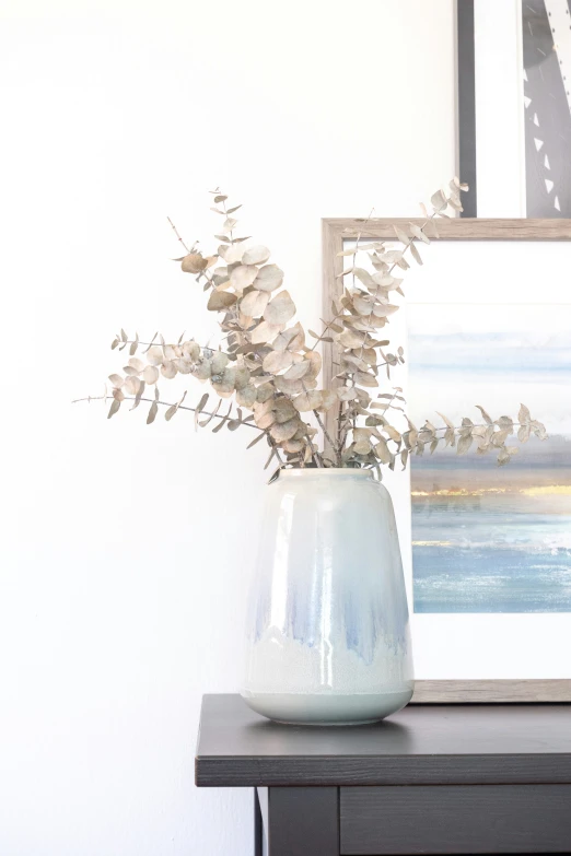 a vase of flowers on a table next to two paintings