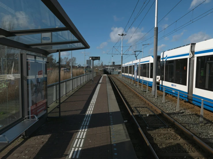 two trains at a train station with wires above them