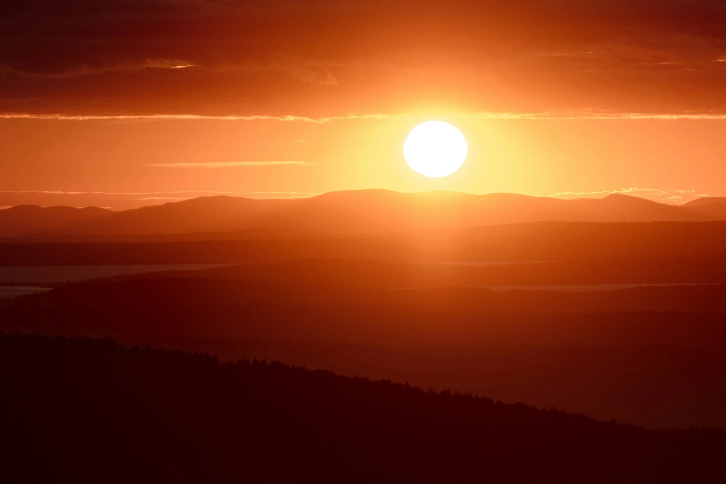 a large orange and yellow ball is setting in the sky