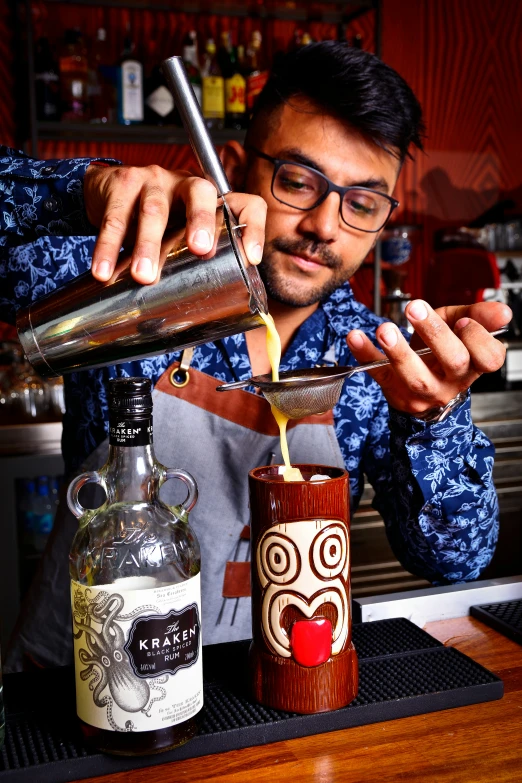 a man pouring a drink into a jar