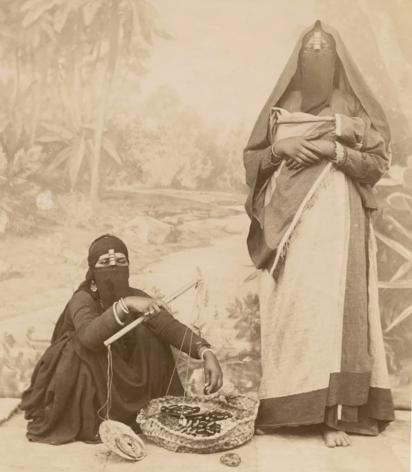 a sepia image of two women sitting and one standing