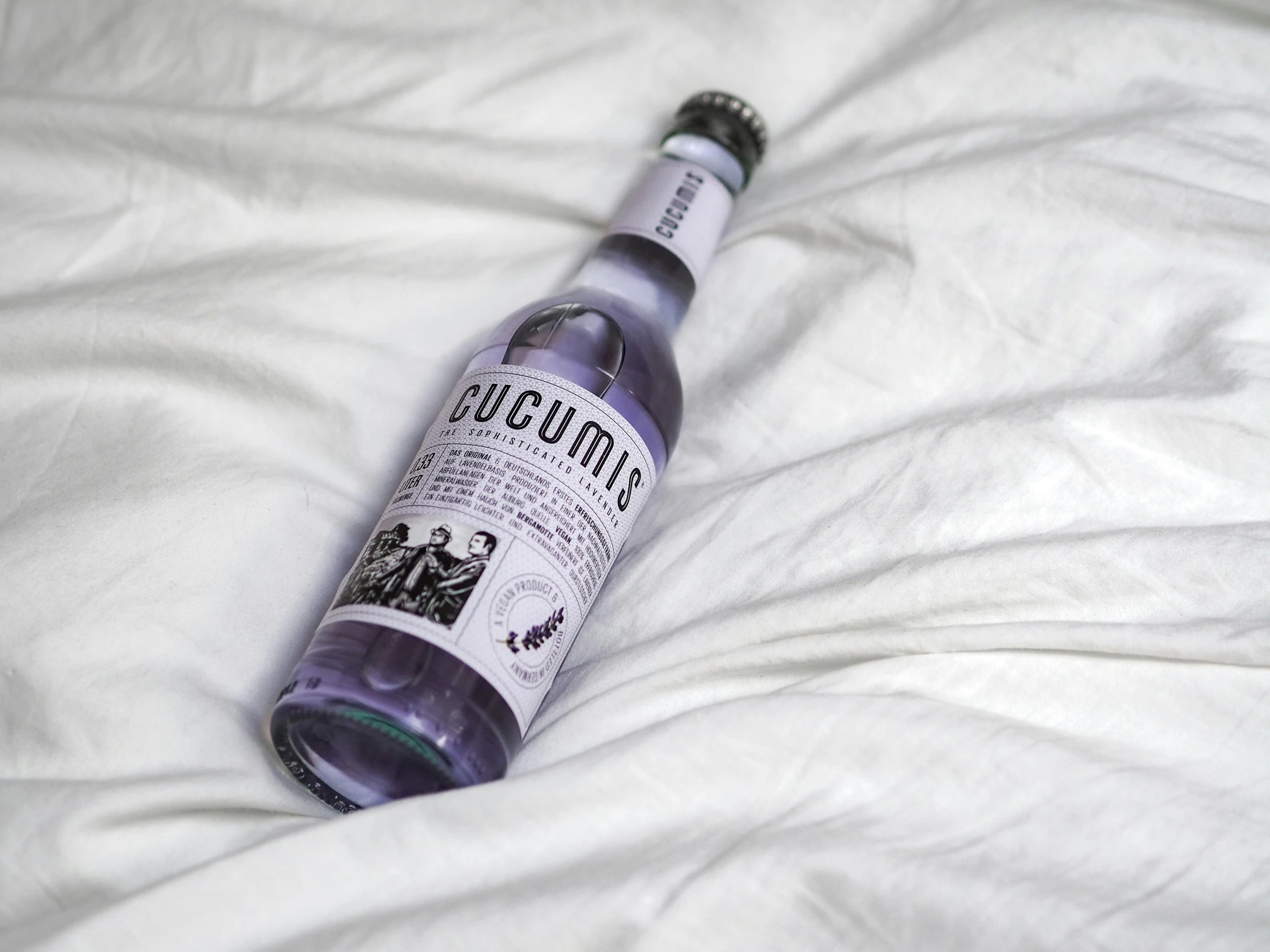 a bottle of alcohol sitting on top of a white blanket