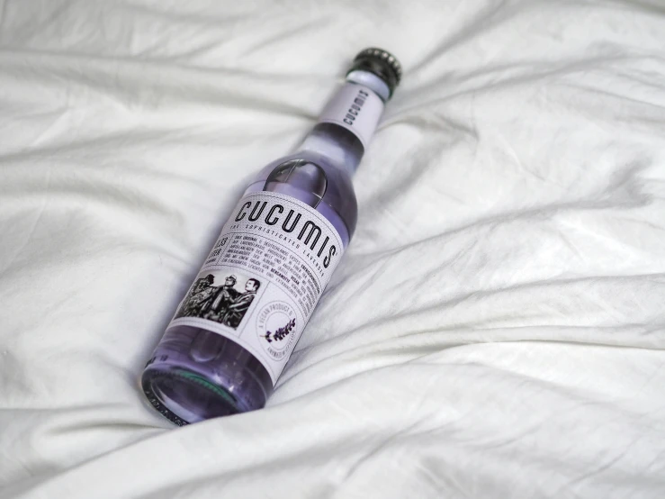 a bottle of alcohol sitting on top of a white blanket