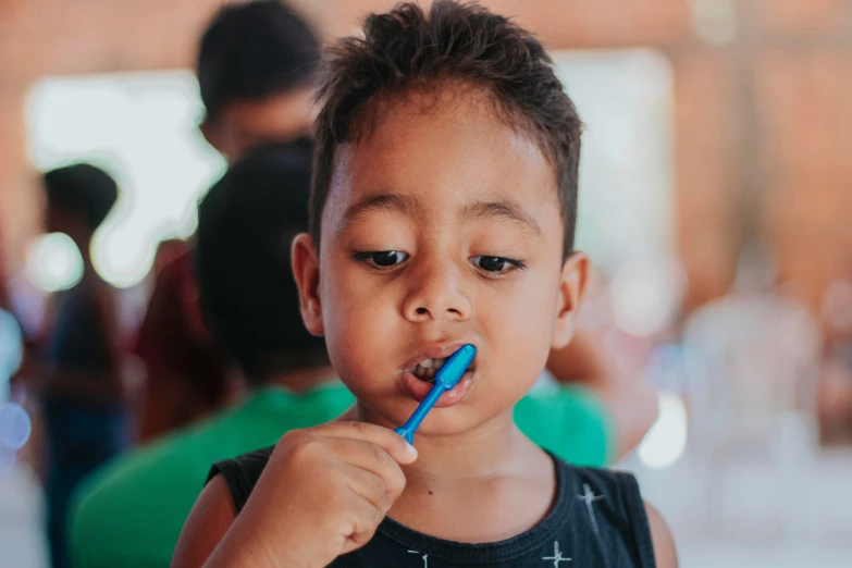 the small boy is brushing his teeth with an electric toothbrush