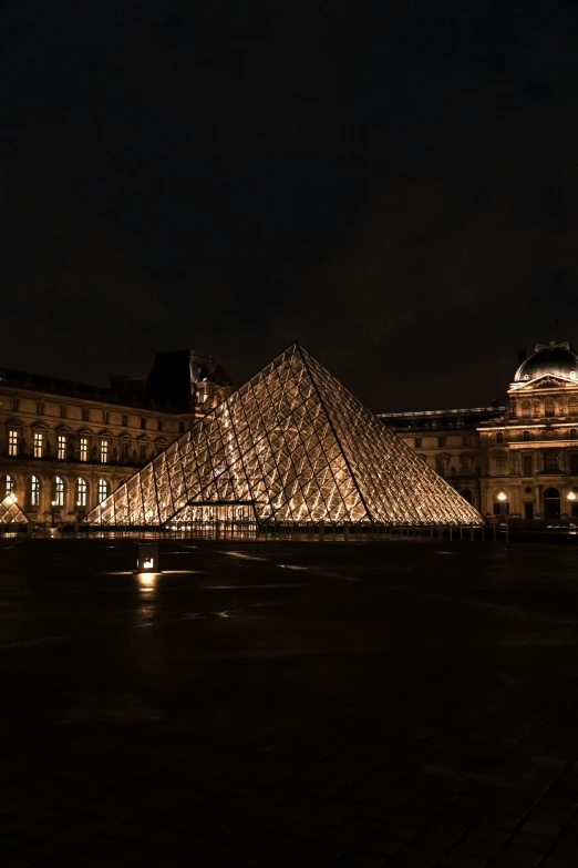 the building has a big glass pyramid in front of it