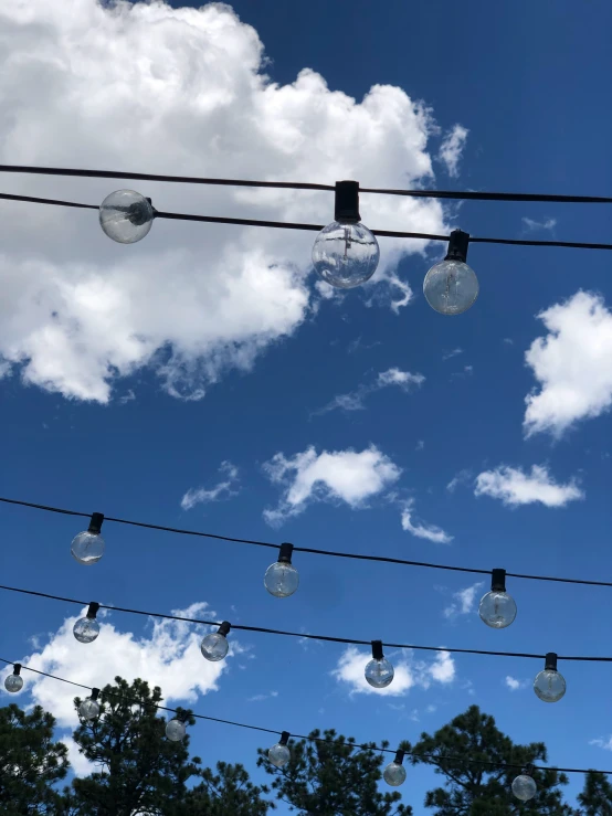 a bunch of light bulbs on a wire with clouds in the background