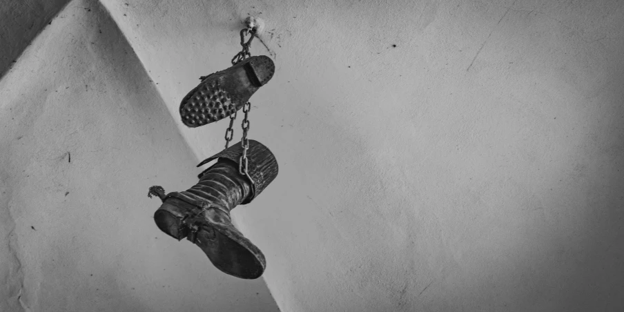 a person is wearing boots on their feet dangling from a chain