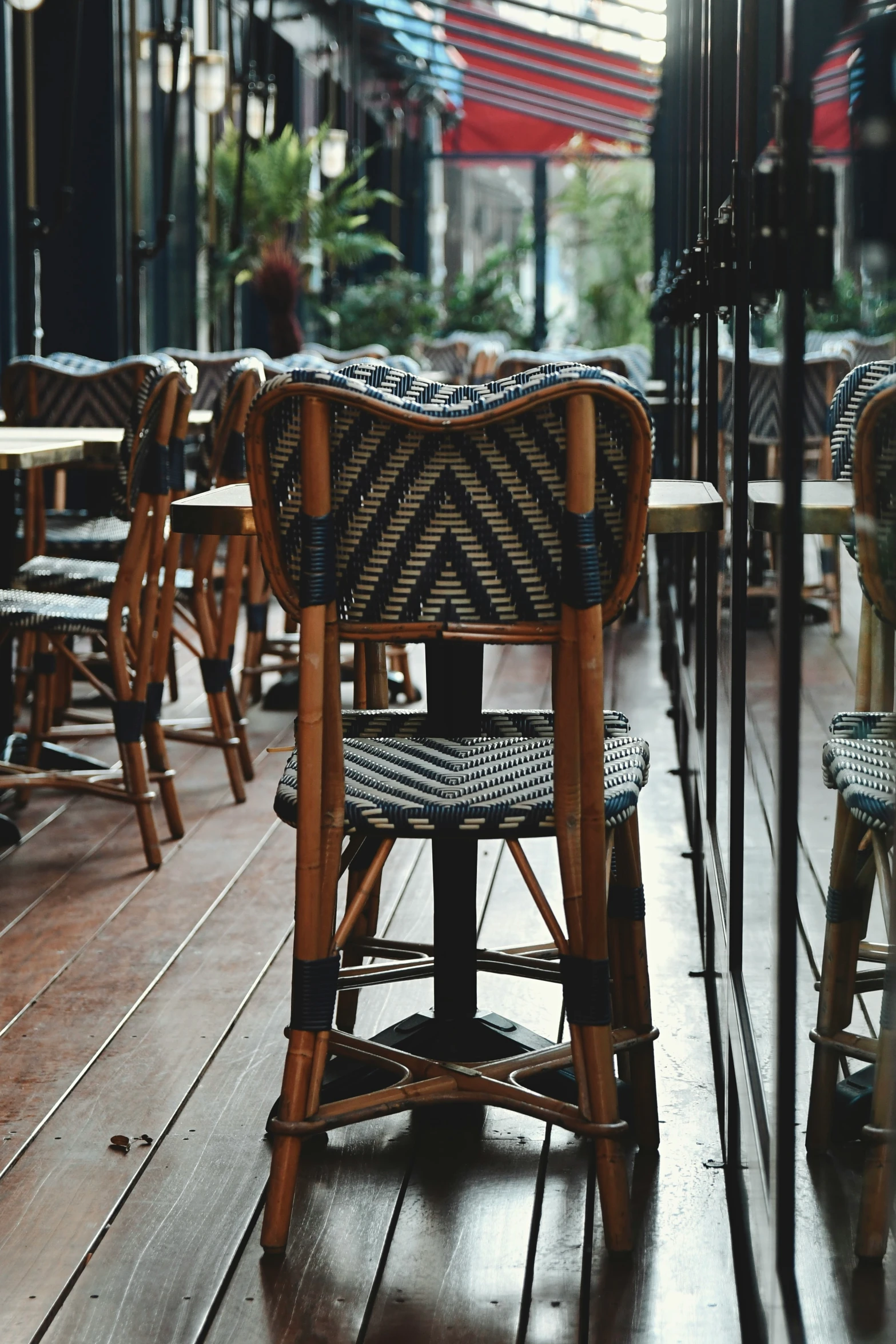 tables lined with wicker chairs on wooden floor next to buildings