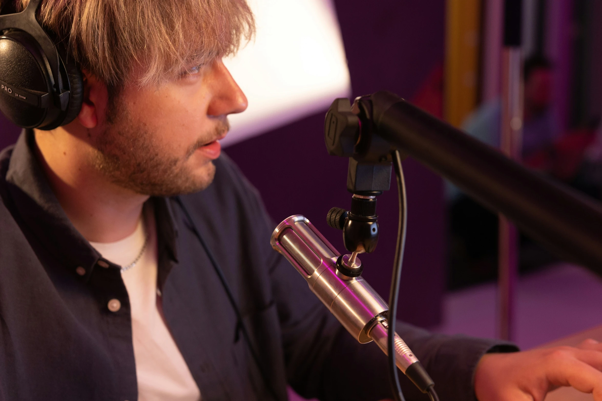 a man in headphones and jacket working in front of a microphone