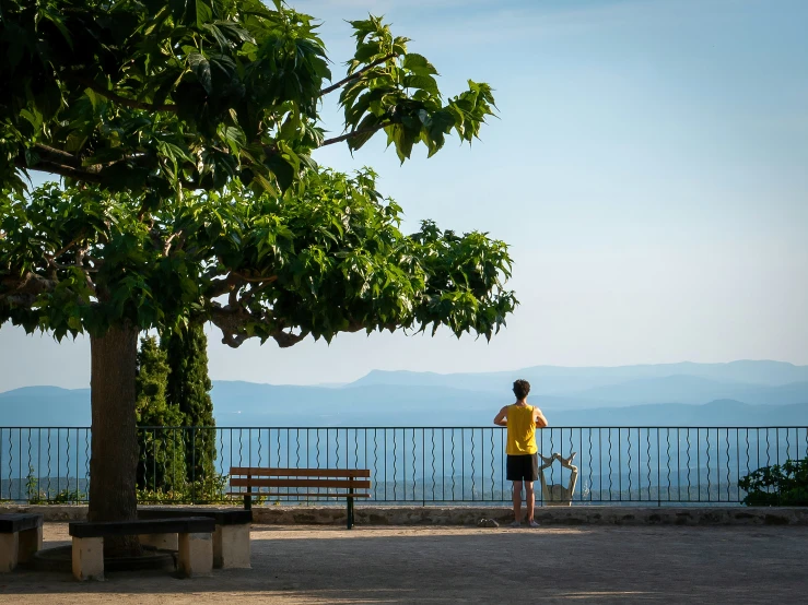 a man standing by the edge of a lake near a bench