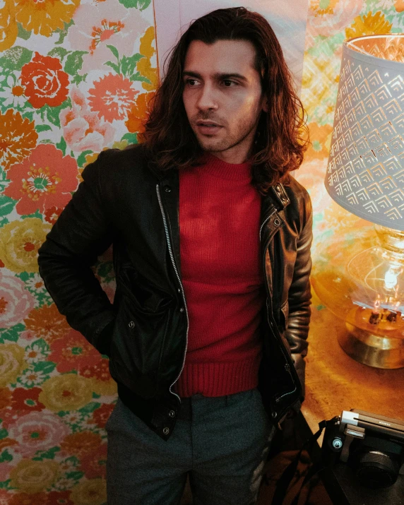 a man is posing for a picture in front of an ornate wall