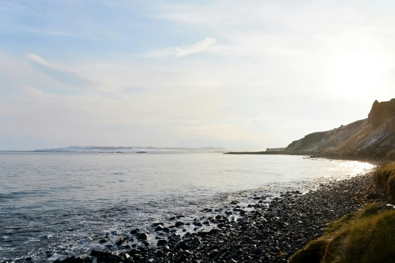 the coast of a body of water surrounded by a hillside