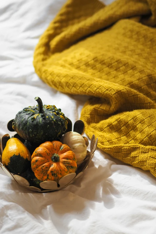 a basket of squash and gourds is on a bed