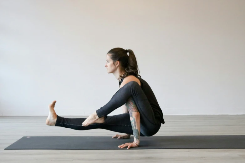 a woman sitting on a yoga mat doing an upward lunge pose