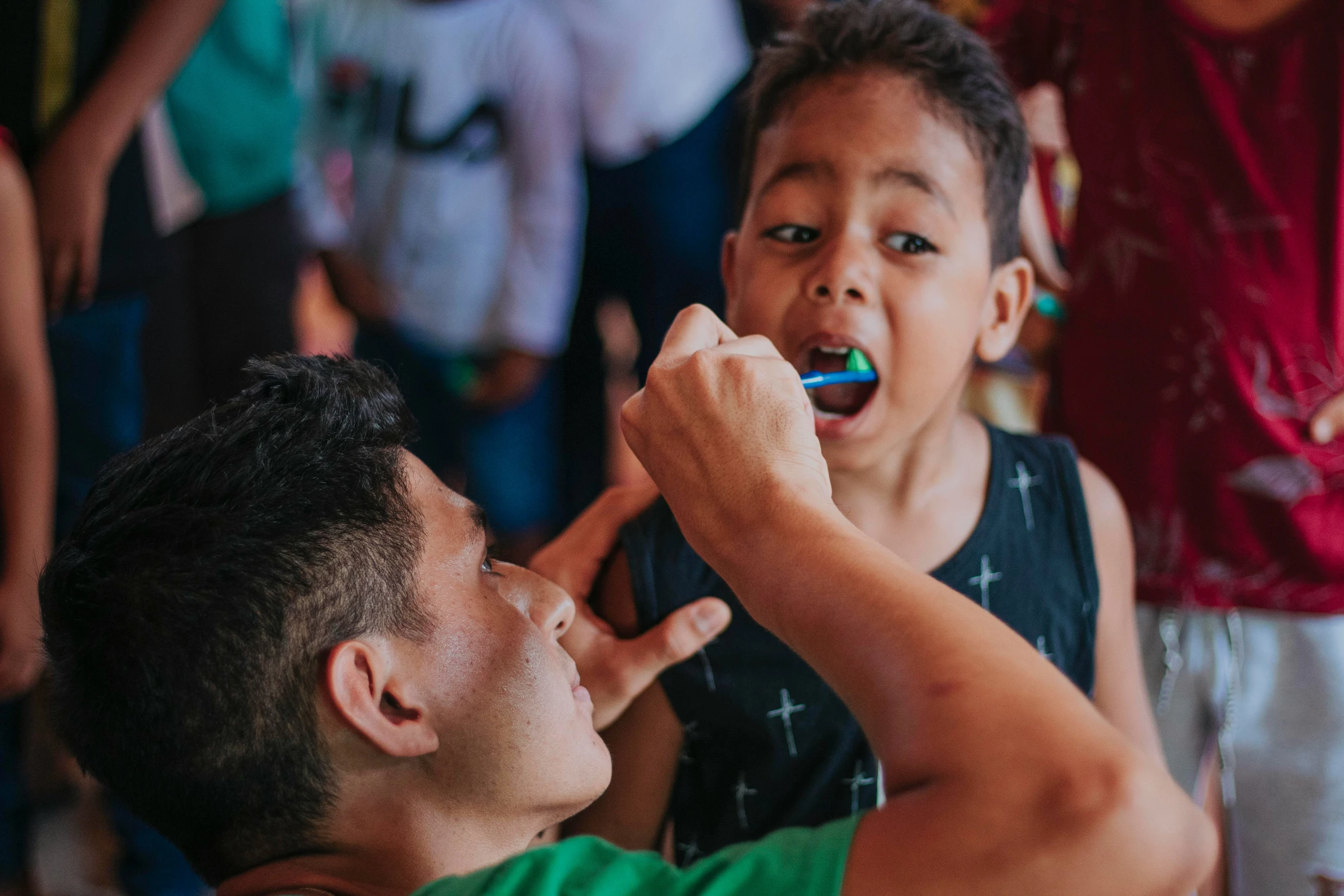 a little boy is brushing his teeth next to an adult