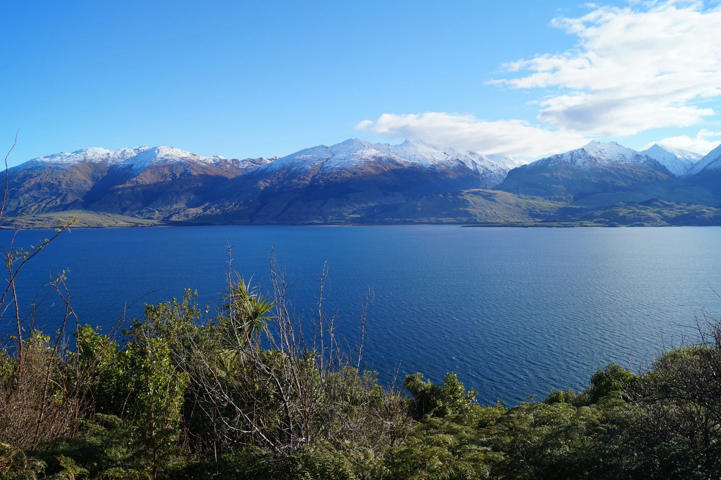 a lake in the middle of a mountain range with snow on the tops