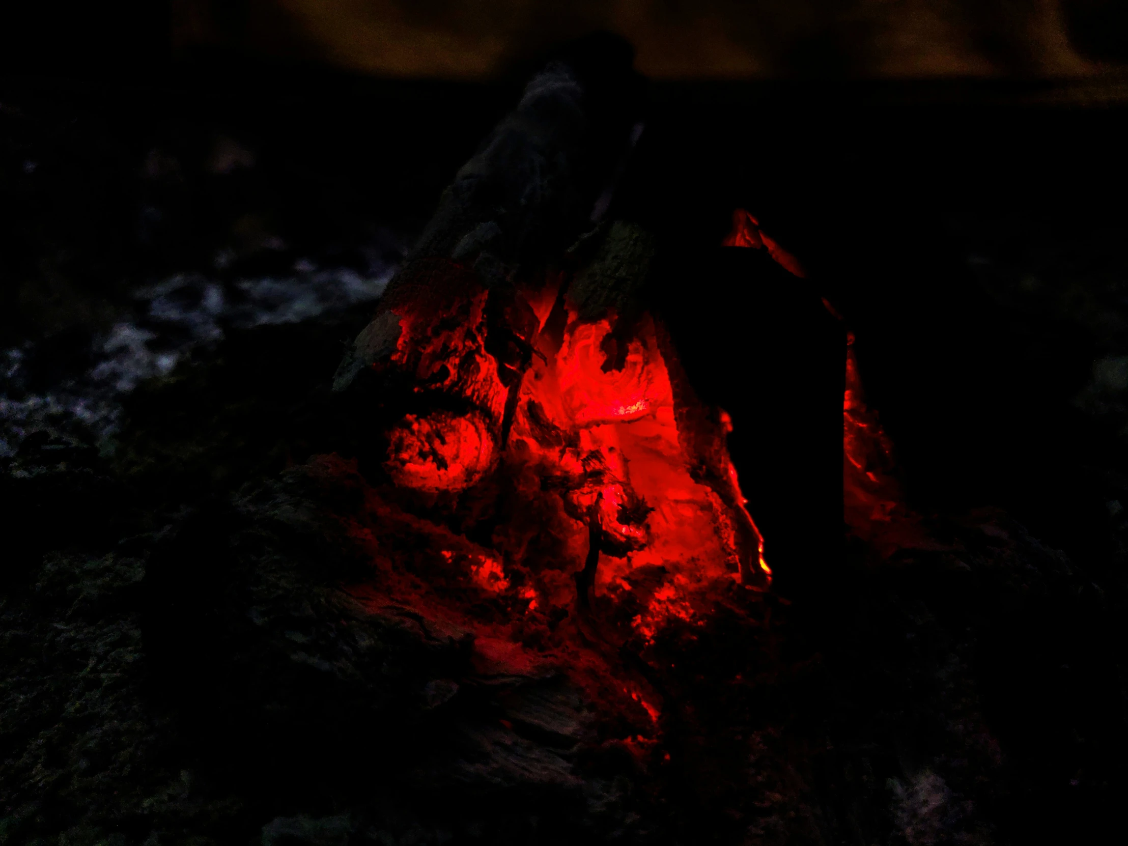 a fire with red flames burning next to some rocks