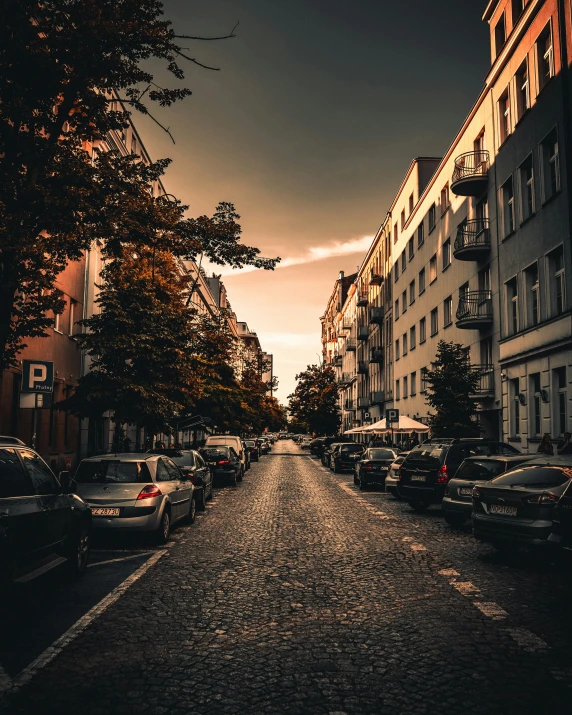 a dark city street is lined with parked cars