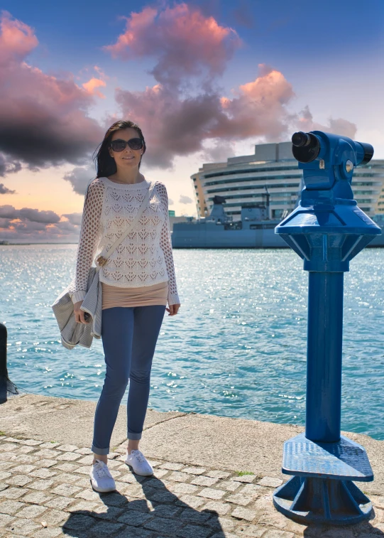 a girl stands by a statue with a sky in the background