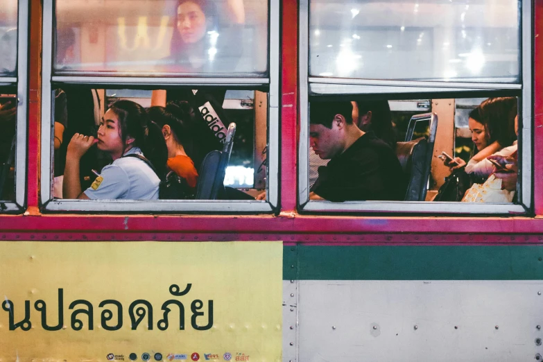 several people sit inside of a bus window