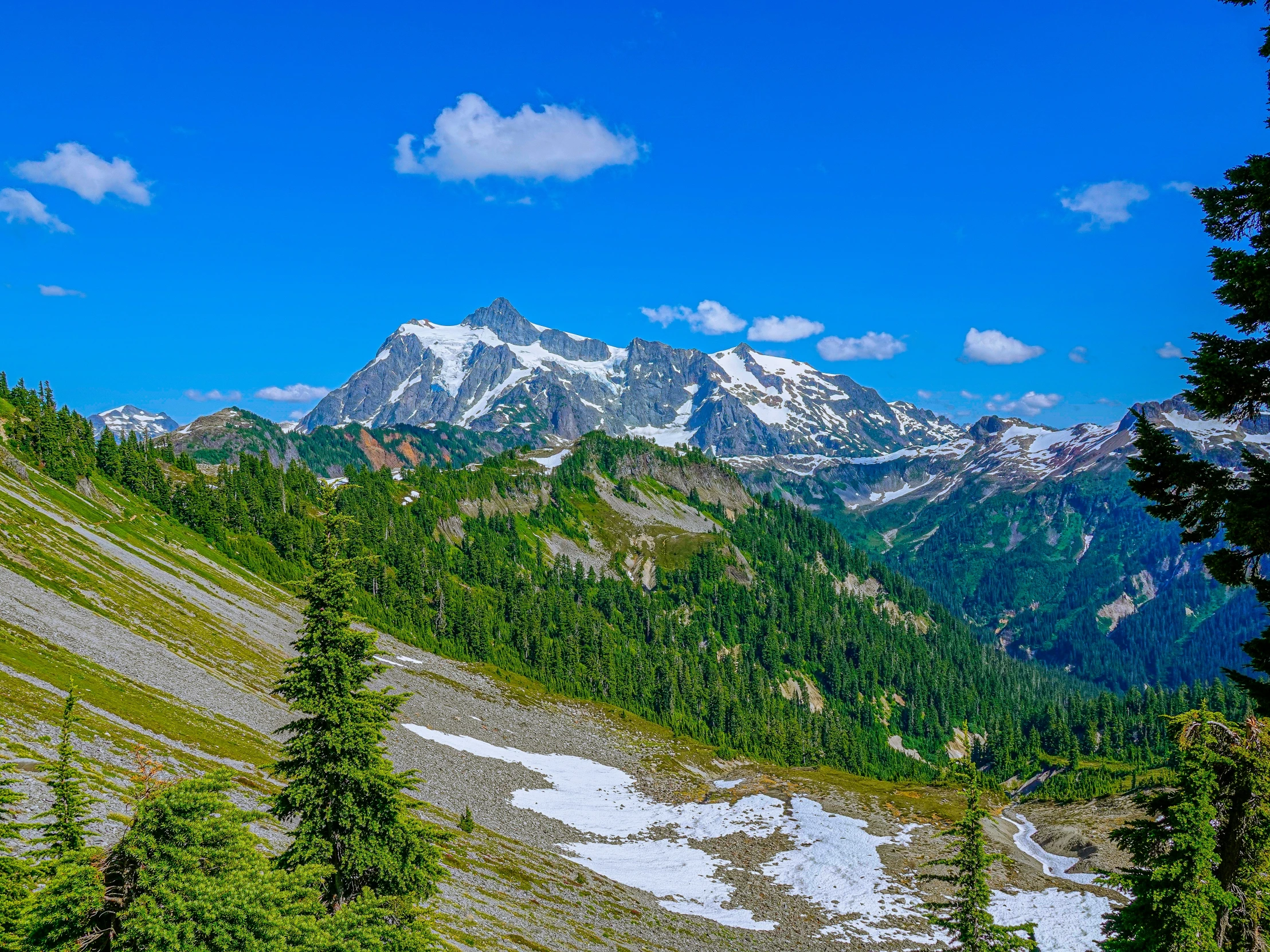 a large hill with snow covered mountains in the distance