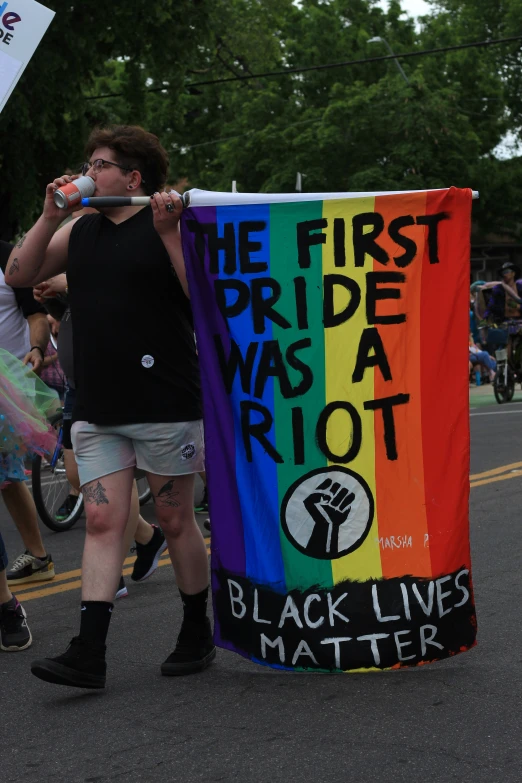 the man is standing outside with his rainbow sign