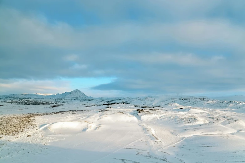 a hill covered in lots of snow with some hills and clouds