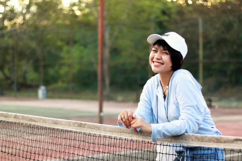 a young woman poses at the net on a tennis court