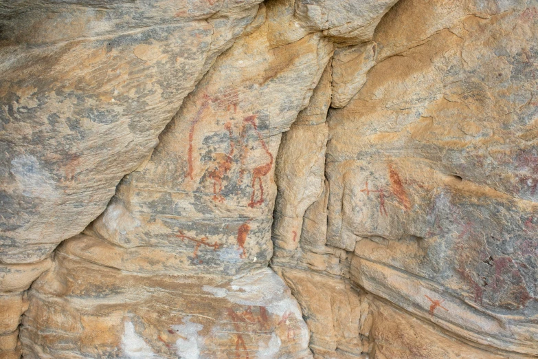 several paintings on rock cliff with different colors and textures