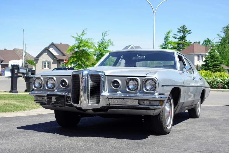 the front end of an old car parked in a driveway