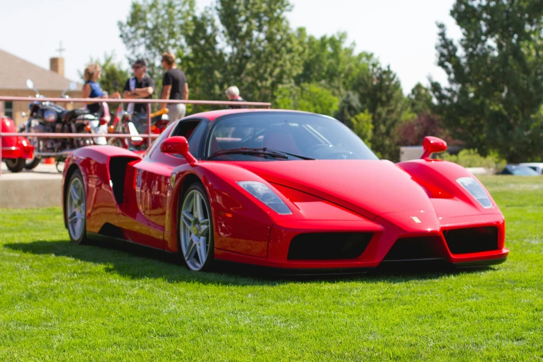 a red car parked in the grass near a field