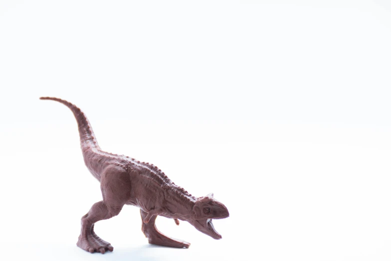 a toy toy dinosaur stands on a white surface