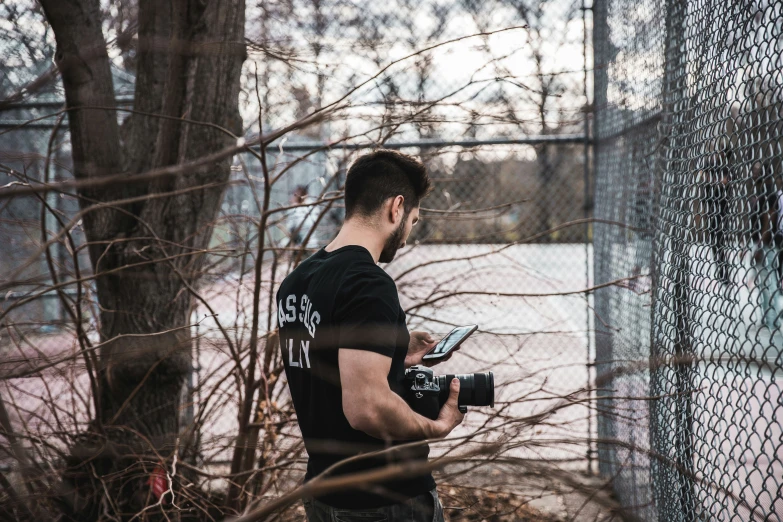 a man is standing in front of a fence holding a camera