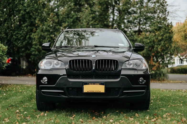 a black and black bmw parked in front of trees