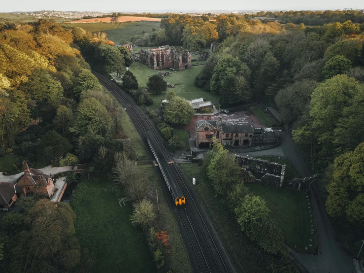 an aerial view of trees, buildings and train tracks