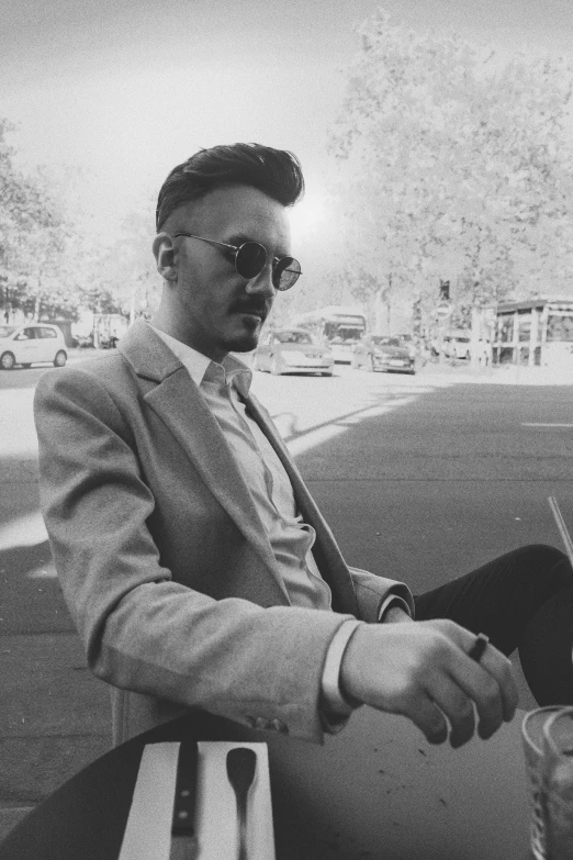 black and white pograph of man in suit sitting on bench