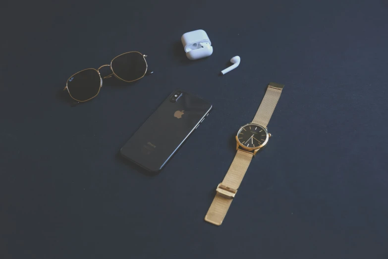 a phone, cellphone, watch and earbuds on a table