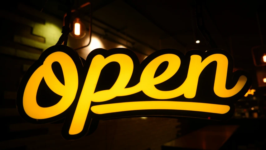 open sign hanging from a wall next to lights