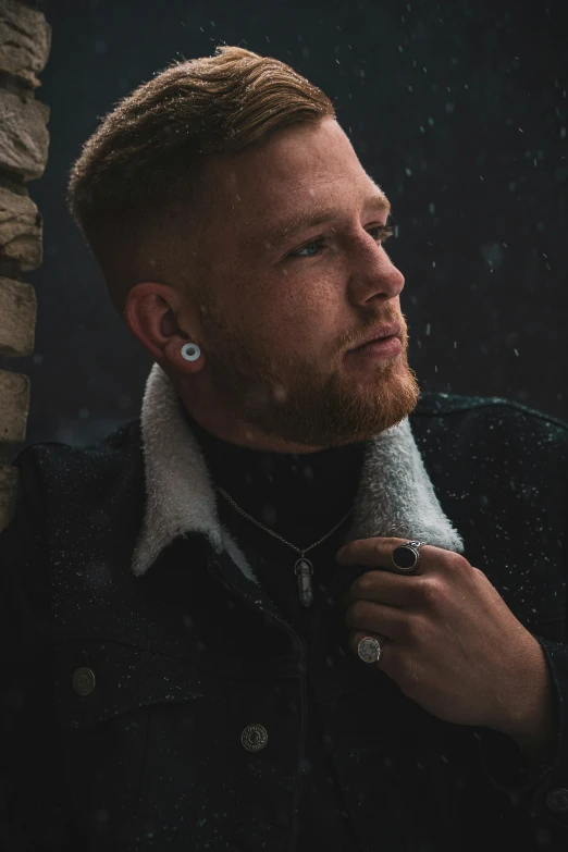 a man wearing earrings holds his hair back from the rain