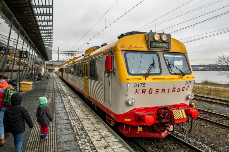 a train is stopped on the tracks and people walking by