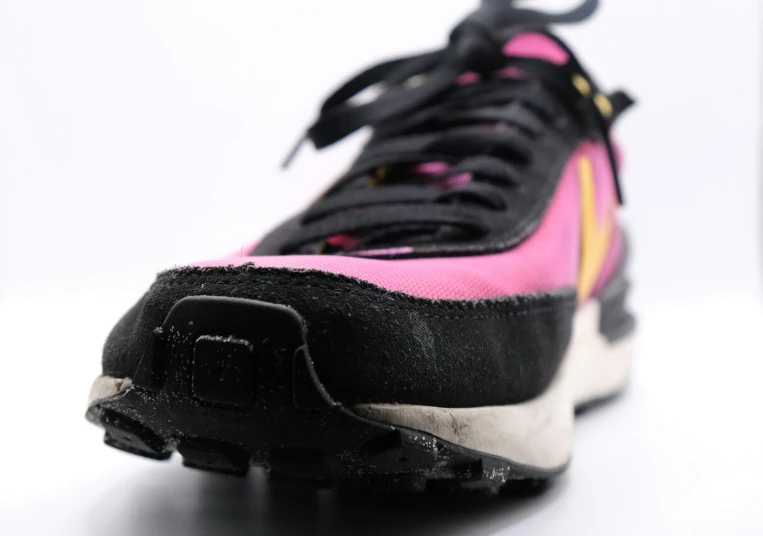 a close up of a black, yellow and pink nike sneaker