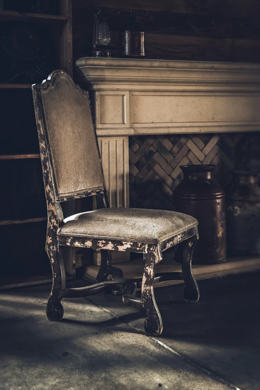 a worn up wooden chair sitting in front of a fireplace